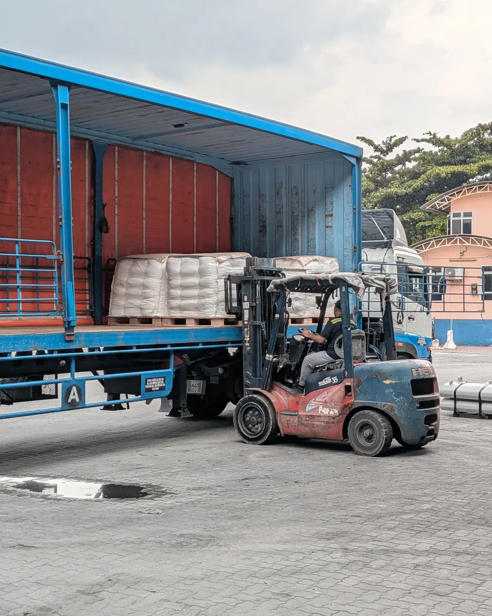 Perdesi açılmış bir kasaya forkliftle yandan palet yükleniyor